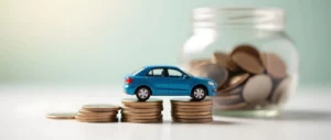 Blaues Spielzeugauto auf gestapelten Münzen, dahinter ein Glas mit Münzen; steht für Sparen oder Planen von Autoausgaben wie ein Reifenplatzer.